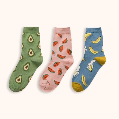 Três pares de meias infantis coloridas com padrões de frutas: abacate, melancia e banana.