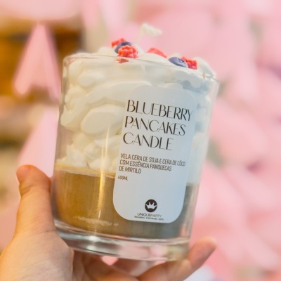 Vela em copo de vidro que imita panquecas com chantilly e frutas