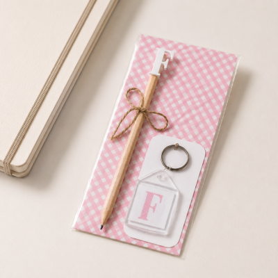 Conjunto lápis e porta-chaves com letra F em padrão rosa e branco