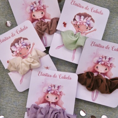 Elásticos de cabelo coloridos em cartões com ilustração de menina e texto