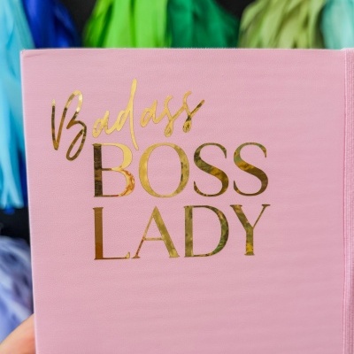 Caderno rosa com texto dourado 'Badass BOSS LADY' e fundo colorido