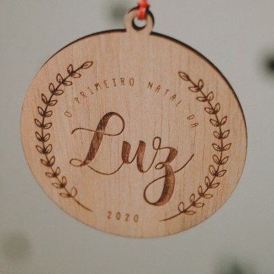 Ornamento de Natal redondo em madeira gravado com texto e ramos decorativos