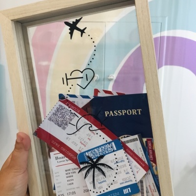 Moldura transparente com passaporte e bilhetes de avião, e desenhos de avião, coração e palmeira.