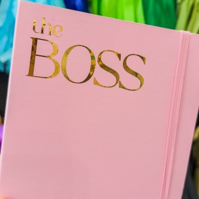Caderno cor-de-rosa com texto dourado 'the BOSS' e elástico para fecho