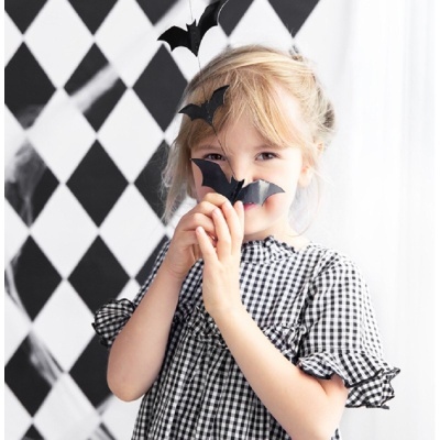 Criança com vestido xadrez preto e branco e morcego decorativo preto