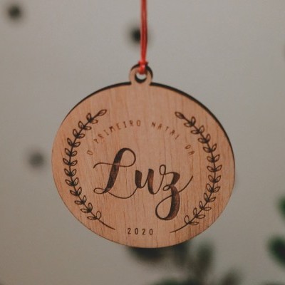 Ornamento de madeira redondo com escrita e cordão vermelho suspenso