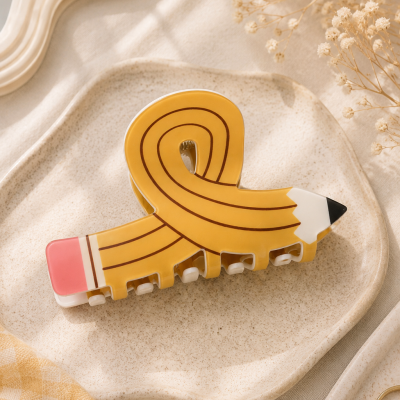 Presilha de cabelo em forma de lápis amarelo numa bandeja cerâmica creme