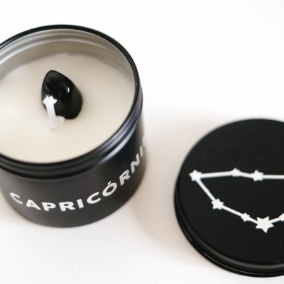 Vela em frasco preto com inscrição CAPRICÓRNIO e tampa com constelação branca