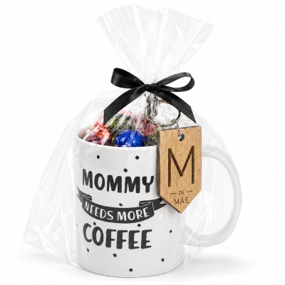 Caneca branca com texto MOMMY NEEDS MORE COFFEE embrulhada em celofane com fita preta e porta-chaves de madeira.