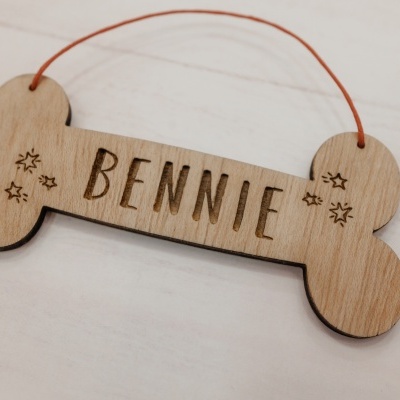 Etiqueta para cães em madeira clara com o nome BENNIE gravado e corda vermelha.