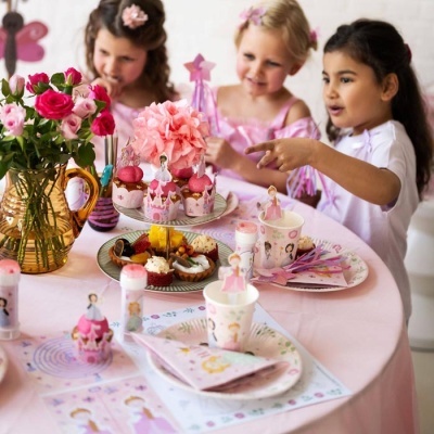 Mesa de festa decorada com tema de bailarinas e flores com três crianças ao fundo