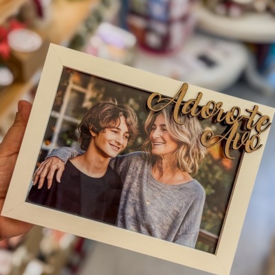 Moldura branca de madeira com foto de mulher e jovem e texto decorativo Adoro-te Avó