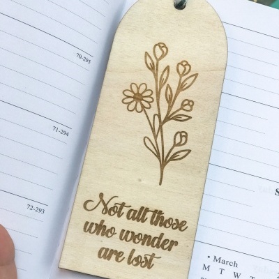 Marcador de livros de madeira com desenho de flores e texto em inglês, sobre agenda de 2025