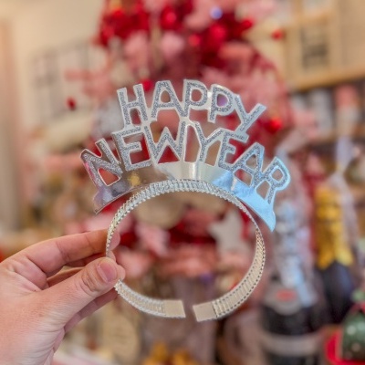 Tiara prateada com a inscrição HAPPY NEW YEAR suportada por uma mão