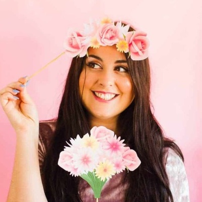 Mulher com coroa de flores a sorrir segurando flores artificiais