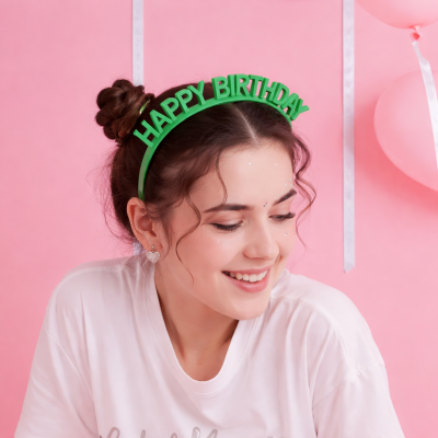 Rapaz com diadema verde com texto HAPPY BIRTHDAY e fundo rosa com balões e fitas