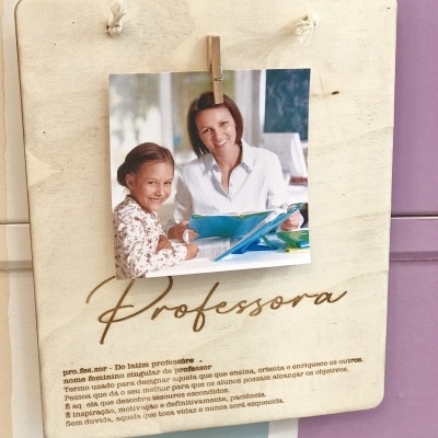 Placa de madeira clara com foto presa e texto gravado 'Professora' e definição em português
