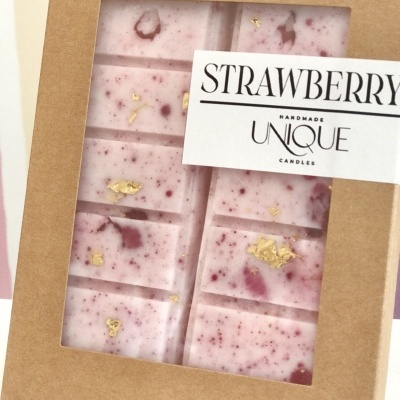 Barra de vela artesanal rosa com manchas roxas em caixa de cartão castanho com rótulo branco