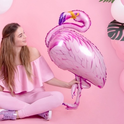 Mulher com roupa rosa segurando balão metálico de flamingo rosa
