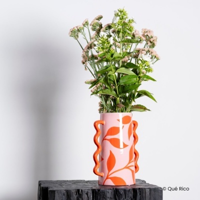 Vaso cerâmico rosa com padrão laranja e flores em superfície preta