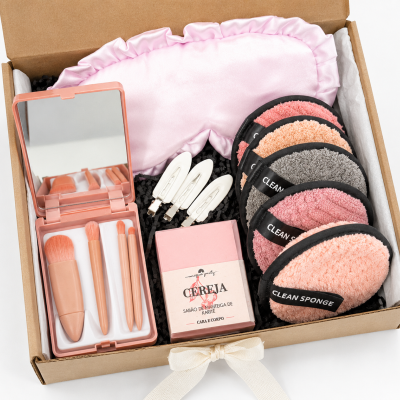 Kit de maquiagem, sabonete, esponjas, presilhas e máscara de dormir numa caixa de presente aberta