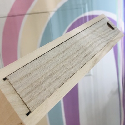 Caixa longa de madeira clara com tampa deslizante e textura natural