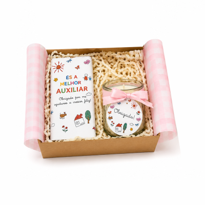 Conjunto de presente com vela de vidro e barra de chocolate em caixa de cartão com papel rosa.
