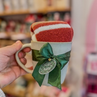 Caneca branca com laço verde e etiqueta com Feliz Natal e tecido vermelho dentro