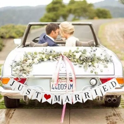 Carro descapotável branco decorado com flores e 'JUST MARRIED' na matrícula