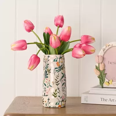 Vaso de cerâmica com tulipas cor de rosa artificiais numa mesa de madeira