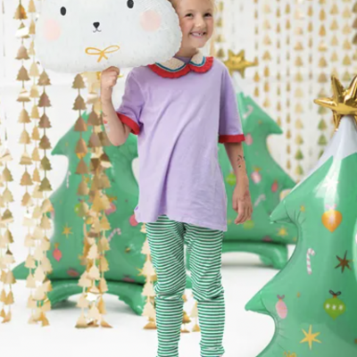 Criança com balão de urso branco segurando em ambiente decorado Natal