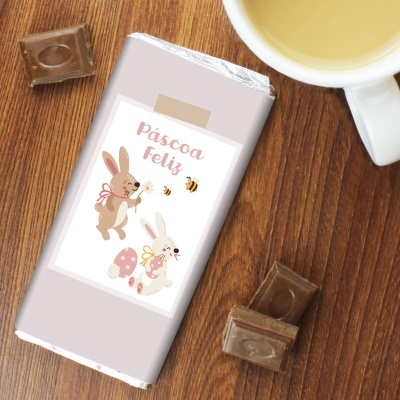 Barra de chocolate com embalagem de Páscoa com coelhos, pedaços de chocolate e chávena branca