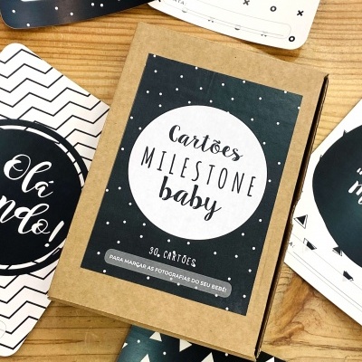 Caixa de cartões milstone baby com cartões decorativos em preto e branco sobre mesa de madeira