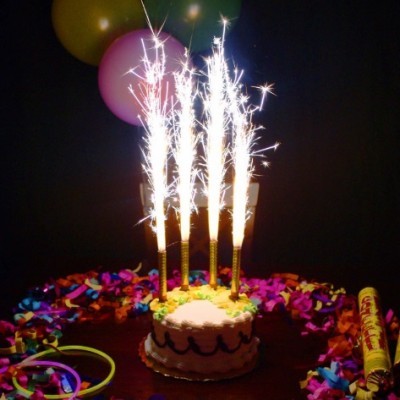 Bolo de aniversário com velas de fogo de artifício e confetes coloridos