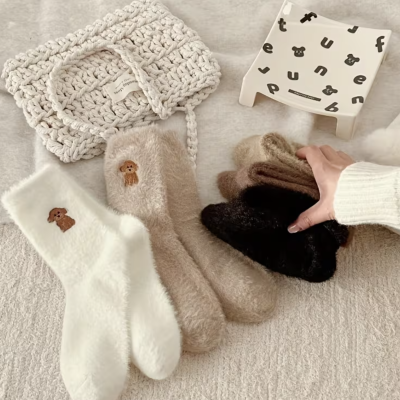 Meias felpudas coloridas com bordado de cão, mala de croché e prato decorado.