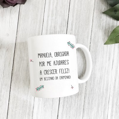 Caneca branca com mensagem e desenhos coloridos numa superfície de madeira clara.