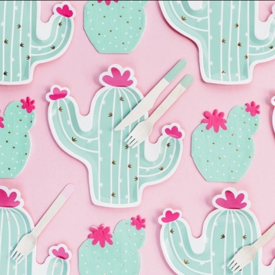 Pratos descartáveis em formato de cactos verdes com flores cor-de-rosa e talheres em fundo cor-de-rosa