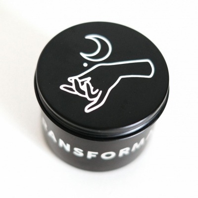 Embalagem preta com tampa decorada com ilustração branca e texto parcial