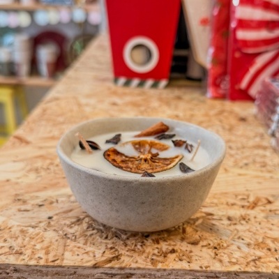 Vela aromática em recipiente de cerâmica com especiarias e fatias de laranja seca