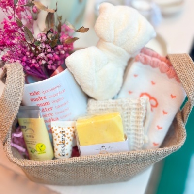 Cesta de presente com flores, caneca com texto, esponja em laço, sabonete, cremes e meias decoradas