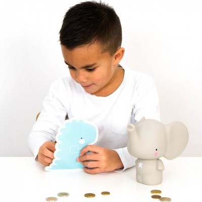 Criança a guardar moedas em cofre dinossauro azul com cofre elefante cinzento na mesa