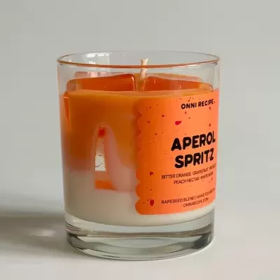 Vela aromática APEROL SPRITZ em copo de vidro com duas camadas de cera laranja e branca