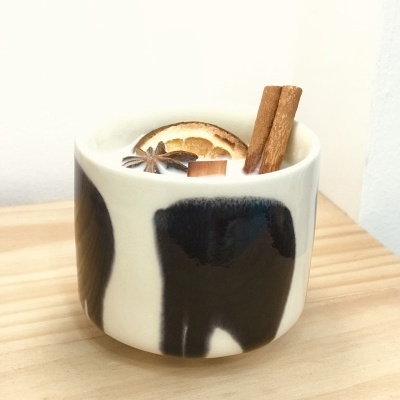 Caneca branca com padrão preto e bebida decorada com especiarias