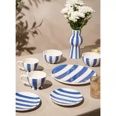 Conjunto de loiça branca com riscas azuis e vaso com flores brancas