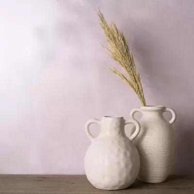 Dois vasos decorativos em cerâmica bege com textura e ramo seco de planta