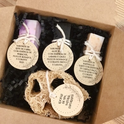 Conjunto de sabonetes artesanais coloridos com etiquetas redondas e esponja natural dentro de caixa de cartão castanho