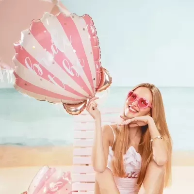 Balão concha rosa e branca com mulher de óculos de sol na praia
