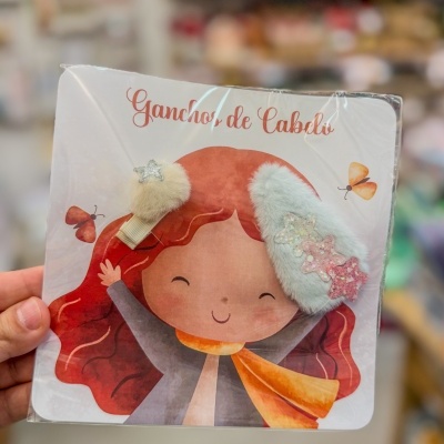Ganchos de cabelo felpudos em embalagem com ilustração e texto em português