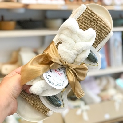 Chinelos bege com tecido castanho, decorados com laço dourado e peluche branco