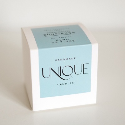 Caixa de vela artesanal branca com etiqueta azul clara e texto UNIQUE CANDLES.